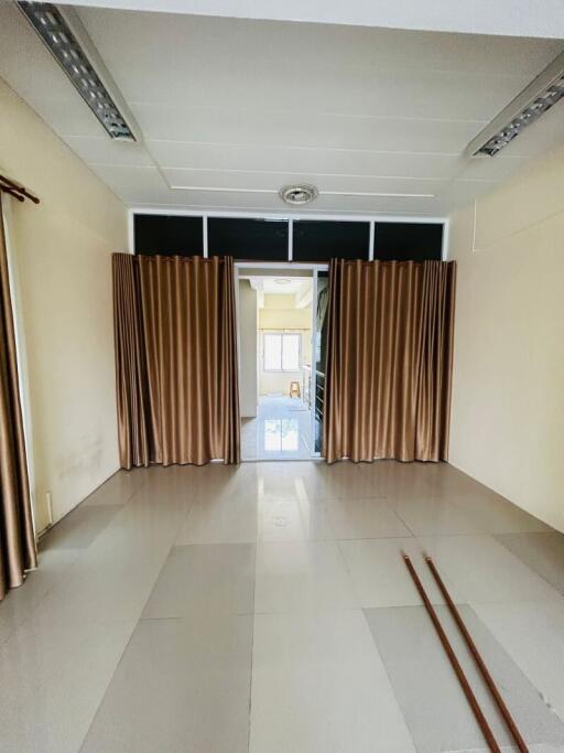 Empty interior space of a building with tiled flooring and window curtains