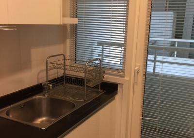 Compact modern kitchen with stainless steel sink and white cabinets