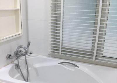 Modern white bathtub with stainless steel fixtures and closed window blinds