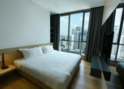 Modern bedroom with a large bed and floor-to-ceiling windows showing city views