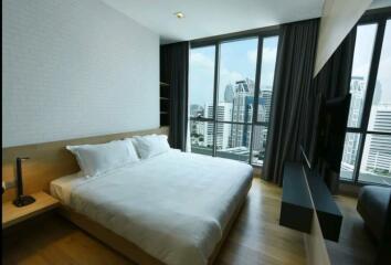 Modern bedroom with a large bed and floor-to-ceiling windows showing city views