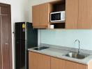 Compact kitchenette with modern appliances and wood finish cabinetry