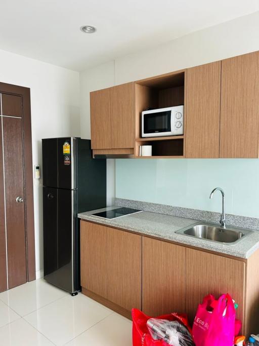 Compact kitchenette with modern appliances and wood finish cabinetry