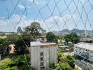 Urban view from behind a safety net showing buildings and green areas