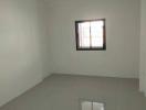 Spacious empty room with tiled flooring and a window