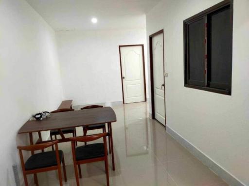 Simple and clean dining area with a wooden table and chairs, with glossy tiled flooring