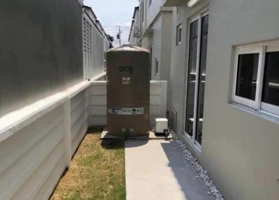 Side yard of a modern residence featuring a walkway and a large water tank