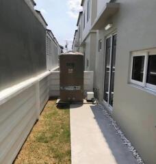 Side yard of a modern residence featuring a walkway and a large water tank