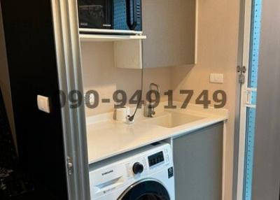 Compact laundry room with modern washing machine and storage shelves