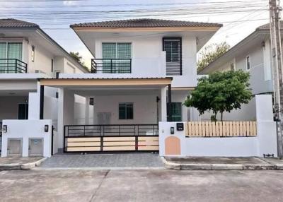 Modern two-story house with white exterior, balcony, and carport