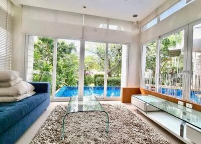 Spacious living room with large windows overlooking a swimming pool