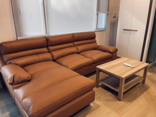 Modern living room with a large brown leather sofa and a wooden coffee table