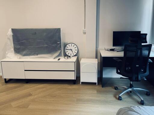 Modern bedroom with a cozy workspace including a desk and office chair, with stylish furniture still wrapped for protection