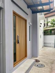 Exterior view of a modern building entrance with a wooden door and a small porch area