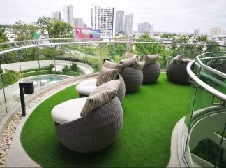 Modern balcony with artificial grass and cozy sitting area overlooking the city