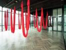 Modern fitness studio with red aerial yoga hammocks and large windows