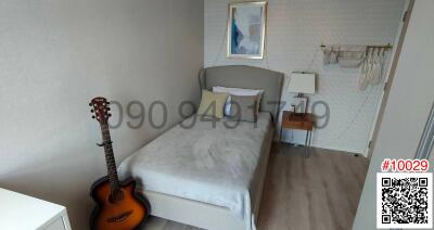 Cozy bedroom with a single bed, guitar, and artwork