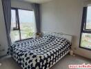 Cozy bedroom with a large bed and cityscape view through large windows