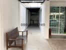 Spacious corridor with tiled flooring, high ceiling, and a wooden bench