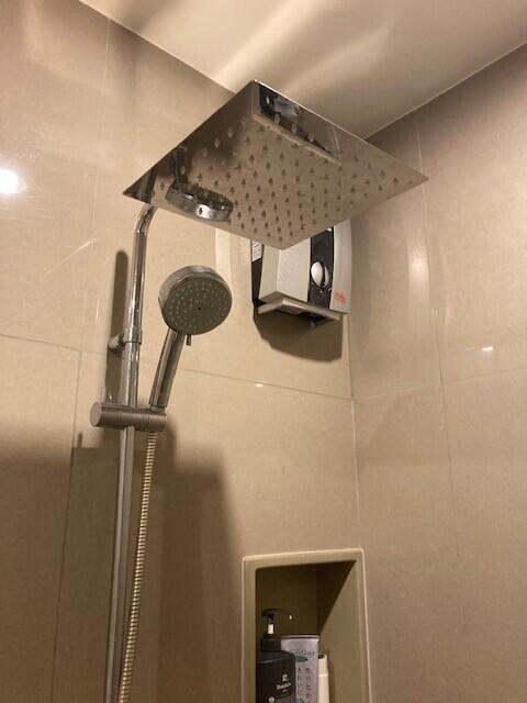 Modern shower head with handheld attachment in a tiled bathroom