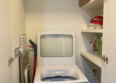 Compact and neat laundry room with storage shelves and a washing machine