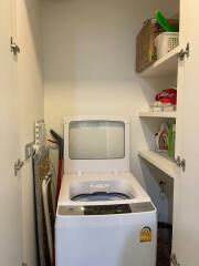 Compact and neat laundry room with storage shelves and a washing machine