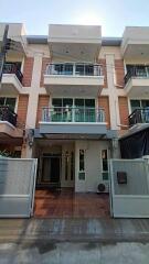 Modern multistory residential building with balconies and a gated entrance