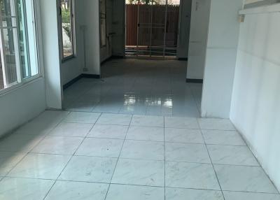 Brightly lit corridor with tiled flooring leading to outside space