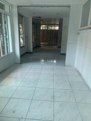 Brightly lit corridor with tiled flooring leading to outside space