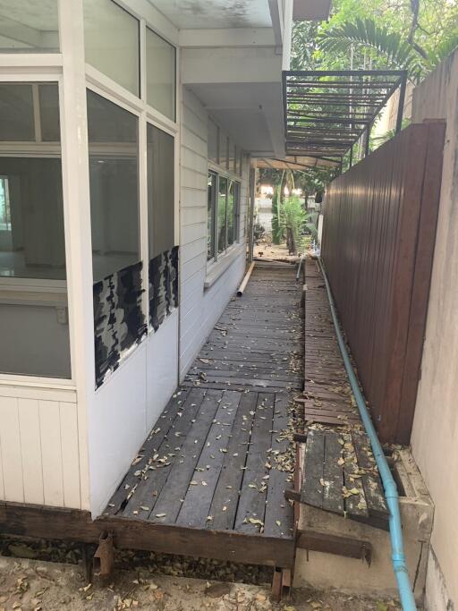 Narrow outdoor walkway with wooden decking next to a house