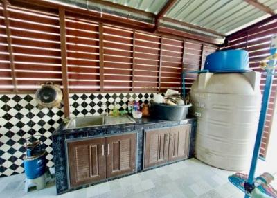 Compact outdoor kitchen with wooden cabinets and large water storage tank
