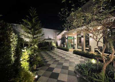 Elegant garden patio with checkered flooring leading to modern home entrance at night