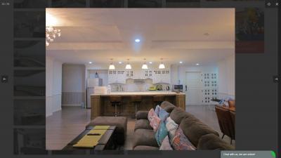Spacious open plan living room with adjacent kitchen and modern lighting