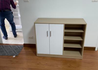 Empty living room with wooden floors and a small storage cabinet