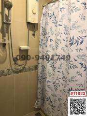 Compact bathroom with floral shower curtain and water heater