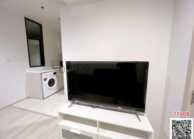 Modern living area with wall-mounted mirror, flat-screen TV, and washing machine