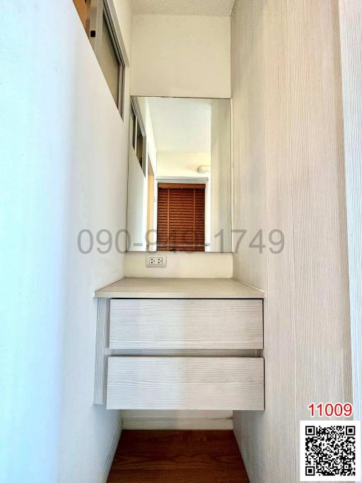Narrow hallway with built-in wooden cabinet and window at the end