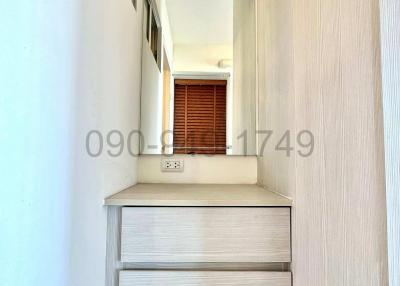 Narrow hallway with built-in wooden cabinet and window at the end