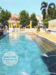 Luxurious outdoor swimming pool surrounded by palm trees with a gazebo and classical architectural elements in a residential estate.