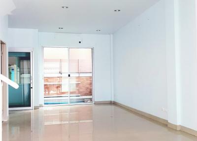 Spacious and well-lit empty living room with tile flooring and glass doors