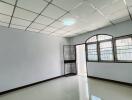 Spacious empty room with glossy tiled flooring and large windows