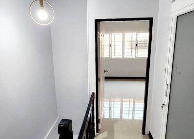 Bright residential hallway with stairway and modern light fixture