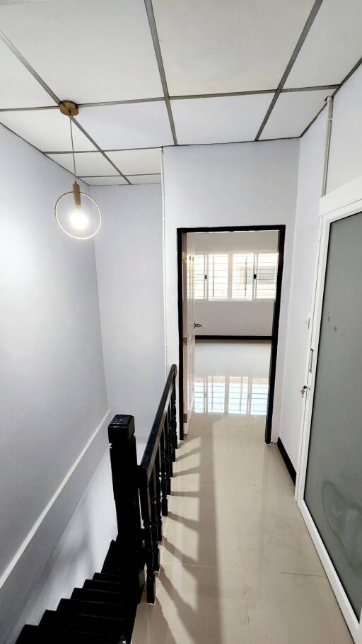 Bright residential hallway with stairway and modern light fixture