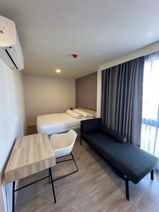 Modern bedroom with an air conditioner, bed, sofa, and a wooden desk