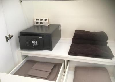 A tidy storage shelf with towels and a safe