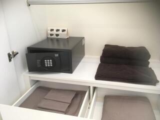 A tidy storage shelf with towels and a safe