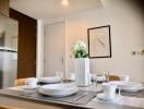 Modern dining area with set table and wall art