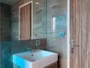 Modern bathroom interior with a wall-mounted sink, large mirror, and elegant tiling