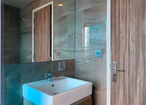 Modern bathroom interior with a wall-mounted sink, large mirror, and elegant tiling