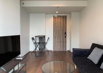 Modern living room interior with a large flat-screen TV, comfortable sofa, and elegant glass coffee table